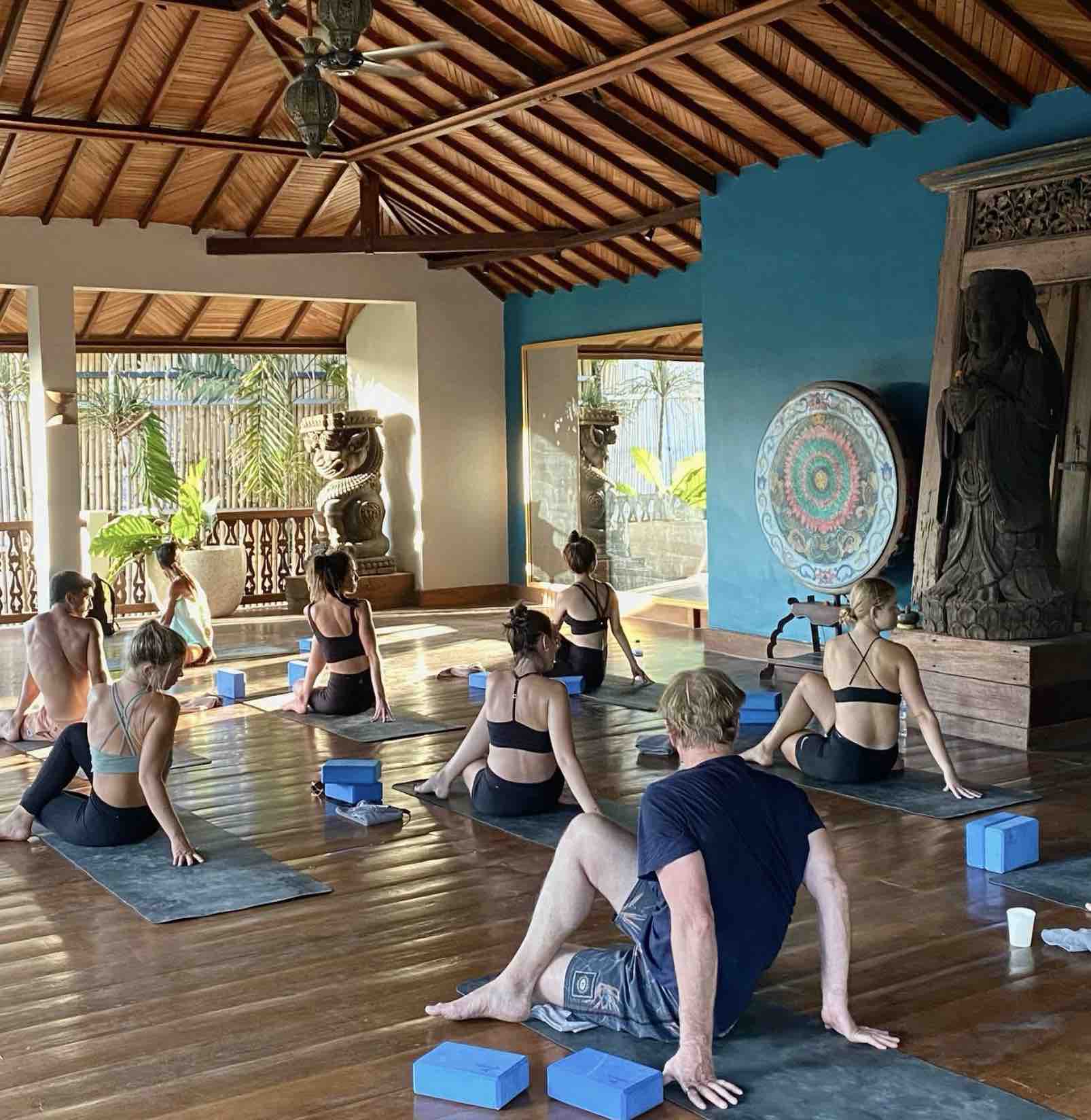 Yoga students following a guided flow on individual mats with space for comfortable movement